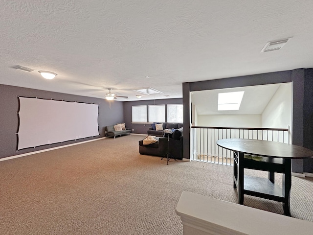 home theater room featuring carpet flooring, a textured ceiling, ceiling fan, and a skylight