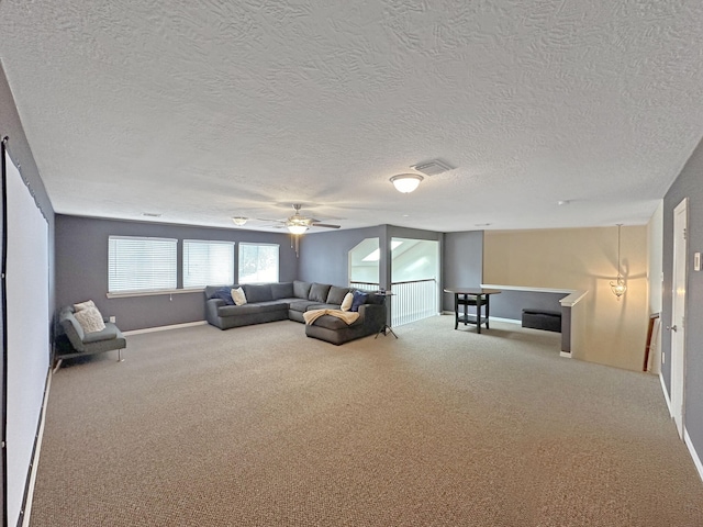 unfurnished living room with carpet flooring, a textured ceiling, and ceiling fan