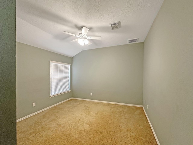 carpeted spare room with lofted ceiling, a textured ceiling, and ceiling fan