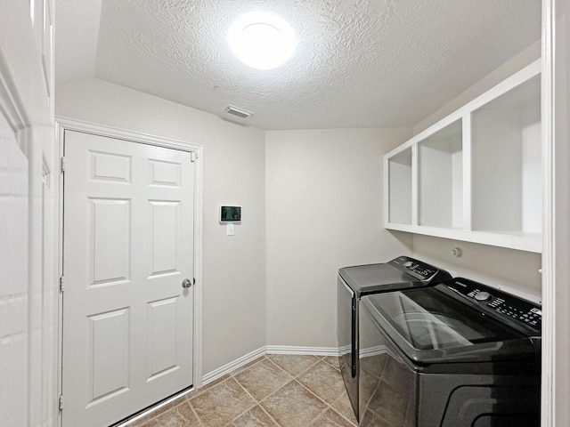 laundry room featuring washing machine and clothes dryer and a textured ceiling