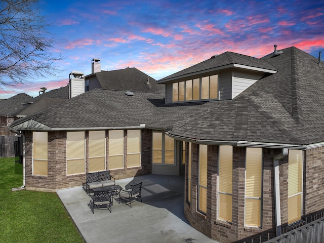 back house at dusk featuring a patio area