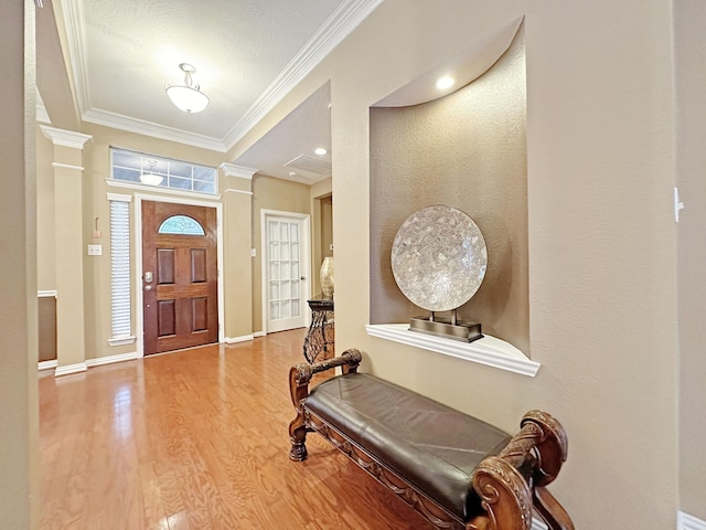 entrance foyer with crown molding, wood-type flooring, and decorative columns