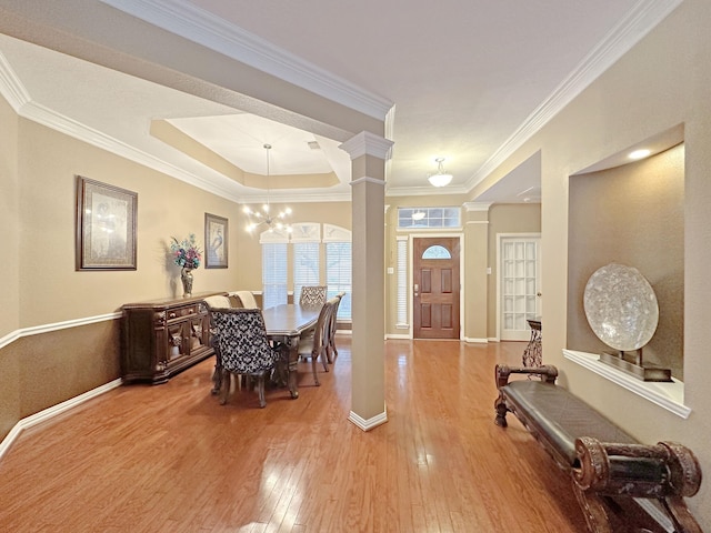 dining area featuring ornate columns, wood-type flooring, crown molding, and an inviting chandelier