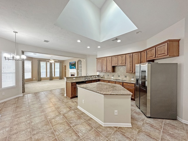 kitchen featuring stainless steel fridge with ice dispenser, tasteful backsplash, sink, black electric stovetop, and kitchen peninsula