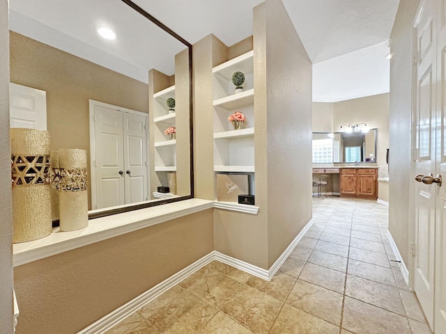 corridor with sink, light tile patterned floors, and built in shelves