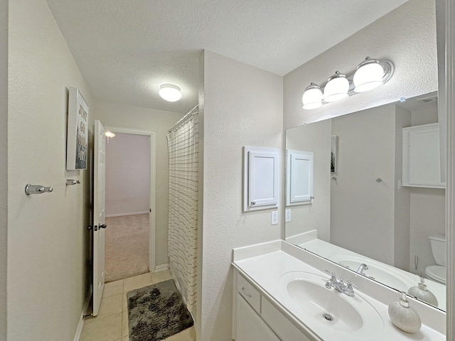 bathroom featuring tile patterned flooring, vanity, walk in shower, toilet, and a textured ceiling