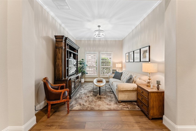 living area with wood-type flooring and ornamental molding