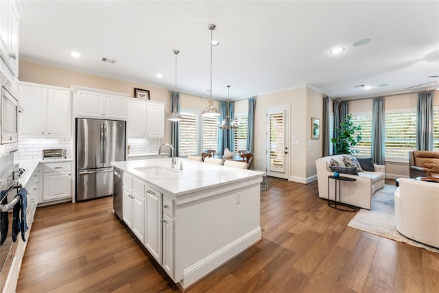 kitchen featuring sink, white cabinets, stainless steel appliances, and an island with sink