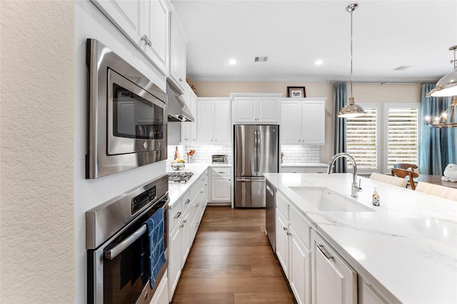 kitchen featuring white cabinetry, stainless steel appliances, tasteful backsplash, pendant lighting, and sink