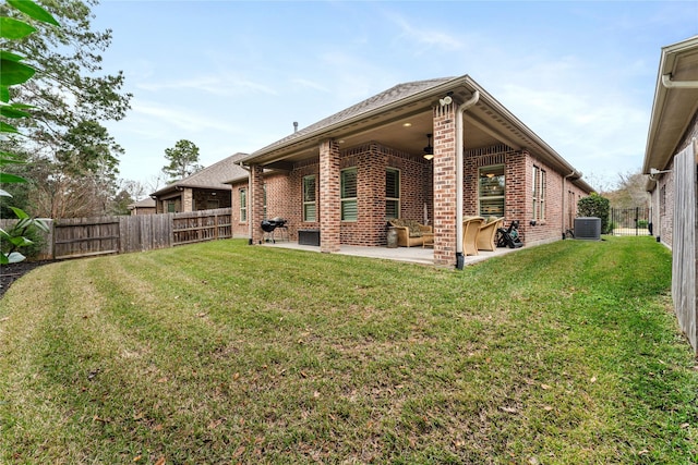 rear view of property with ceiling fan, central air condition unit, a patio area, and a yard