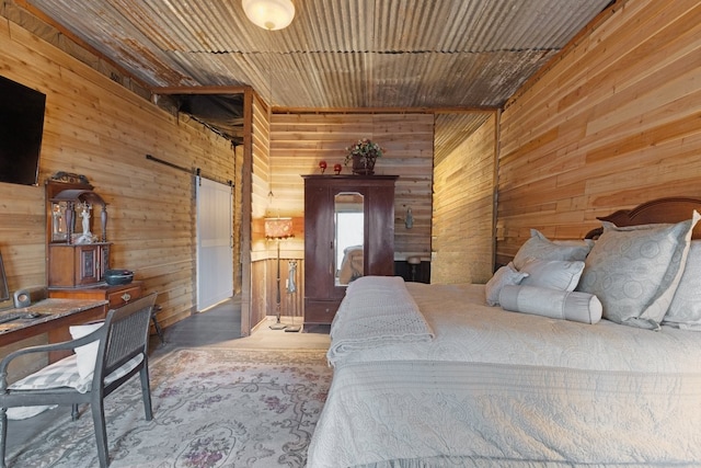 bedroom featuring a barn door and wood walls