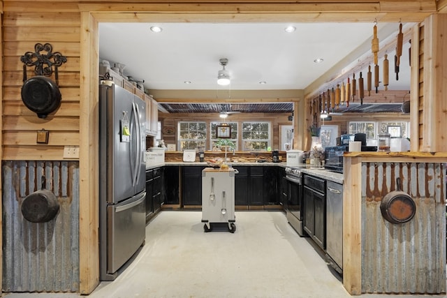 kitchen with light stone countertops, stainless steel appliances, kitchen peninsula, and ceiling fan