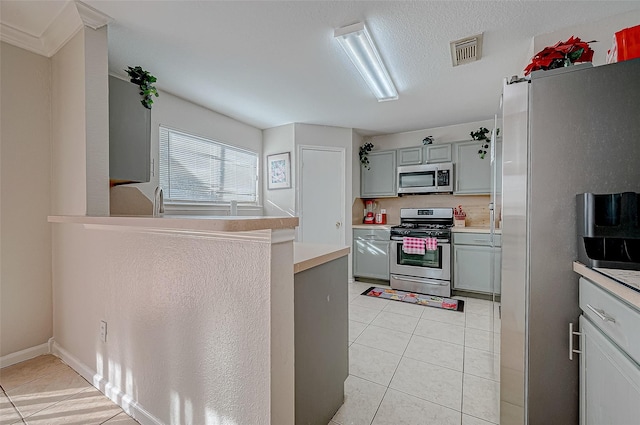 kitchen featuring light tile patterned floors, appliances with stainless steel finishes, gray cabinets, and a textured ceiling