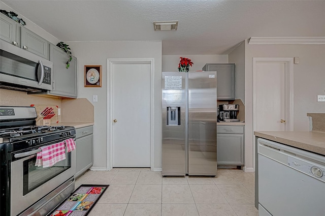 kitchen featuring light tile patterned flooring, gray cabinets, stainless steel appliances, and a textured ceiling