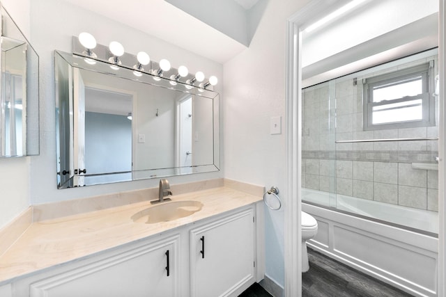 full bathroom featuring toilet, hardwood / wood-style floors, vanity, and shower / bath combination with glass door