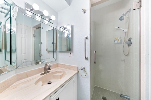 bathroom featuring a shower with shower door and vanity