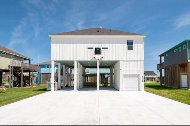 back of property with concrete driveway, a garage, a carport, and a yard