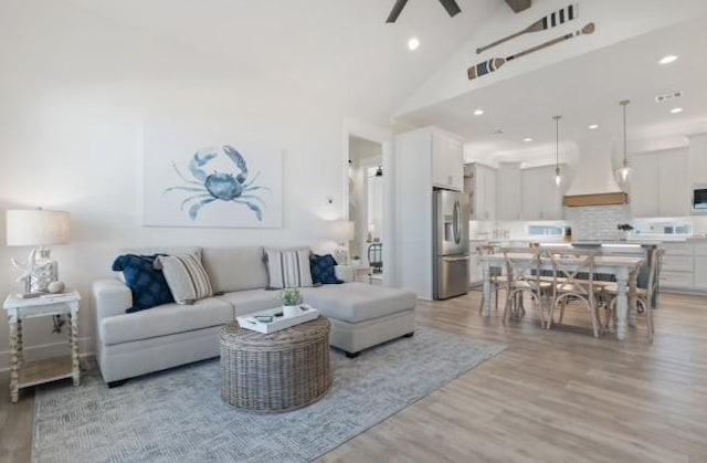 living room featuring high vaulted ceiling, ceiling fan, and light wood-type flooring