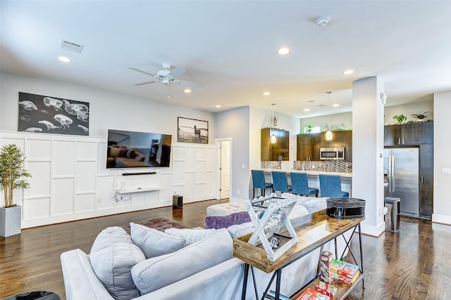 living room featuring dark wood-type flooring and ceiling fan