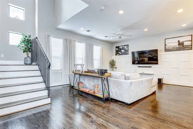 living room featuring dark wood-type flooring and ceiling fan