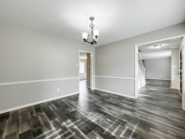 spare room featuring a textured ceiling, dark hardwood / wood-style flooring, and a chandelier