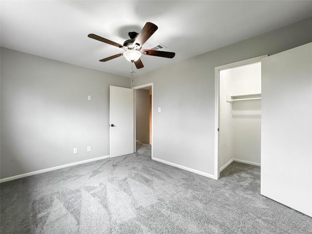 unfurnished bedroom featuring ceiling fan, a walk in closet, light carpet, and a closet