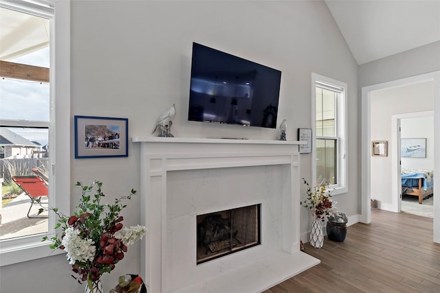 living room with wood-type flooring, a high end fireplace, and lofted ceiling