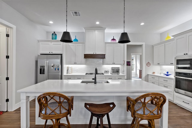 kitchen featuring sink, appliances with stainless steel finishes, an island with sink, and pendant lighting