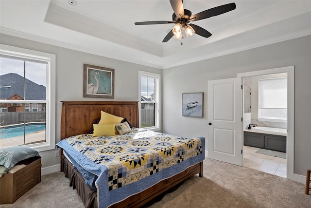 carpeted bedroom featuring ceiling fan, crown molding, a raised ceiling, and ensuite bath