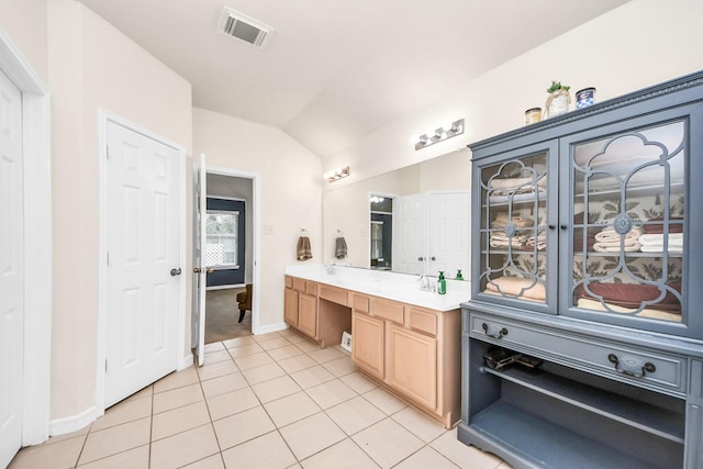 bathroom with tile patterned flooring, vanity, and lofted ceiling