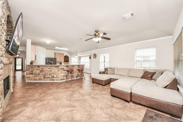 living room with a fireplace, vaulted ceiling, ceiling fan, and plenty of natural light