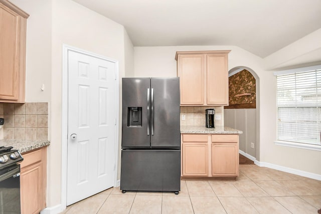 kitchen featuring decorative backsplash, vaulted ceiling, light brown cabinets, and stainless steel refrigerator with ice dispenser