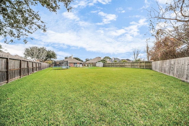 view of yard with a fenced backyard, a trampoline, and a residential view