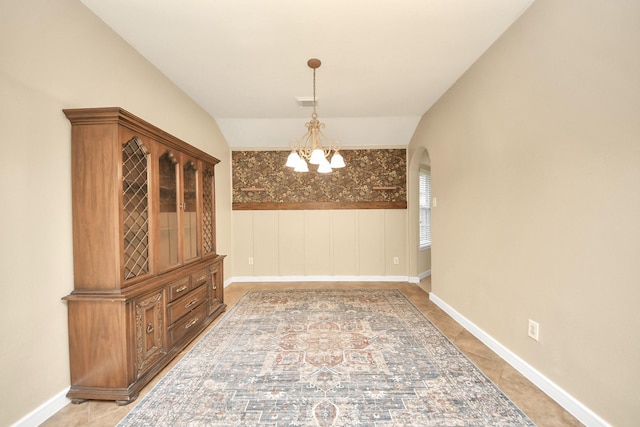 unfurnished dining area featuring visible vents, arched walkways, an inviting chandelier, tile patterned flooring, and vaulted ceiling