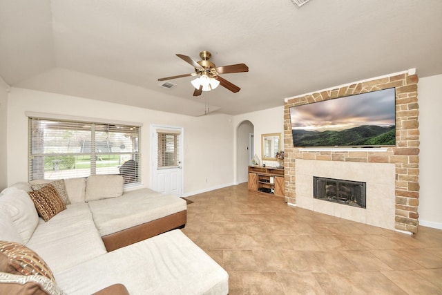 living area featuring a large fireplace, ceiling fan, visible vents, and baseboards