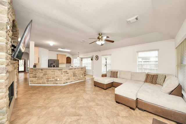 living area with ceiling fan, visible vents, and a stone fireplace