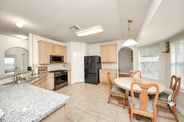 kitchen featuring arched walkways, a sink, visible vents, appliances with stainless steel finishes, and light brown cabinetry