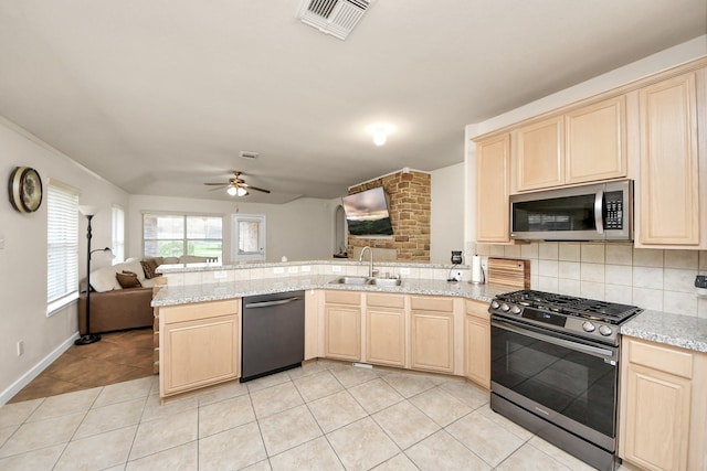 kitchen with stainless steel appliances, backsplash, open floor plan, a sink, and a peninsula