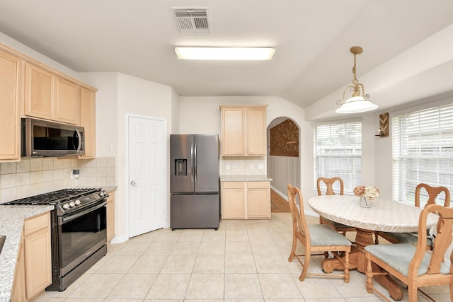 kitchen with light tile patterned floors, visible vents, arched walkways, appliances with stainless steel finishes, and hanging light fixtures