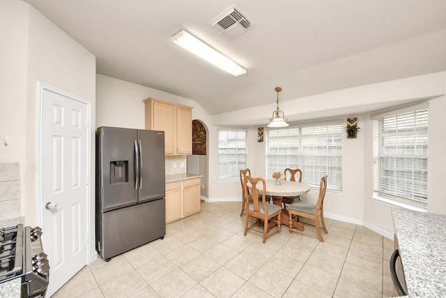 kitchen with visible vents, range with gas stovetop, decorative backsplash, light brown cabinetry, and stainless steel fridge