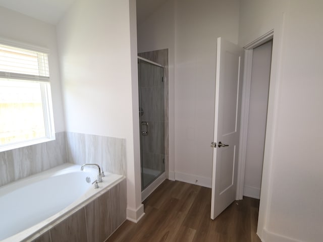 full bathroom with a bath, a stall shower, and wood finished floors