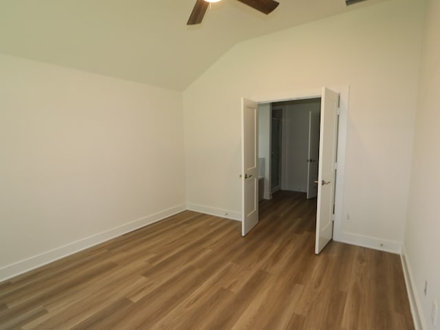 unfurnished bedroom with baseboards, a ceiling fan, wood finished floors, and vaulted ceiling