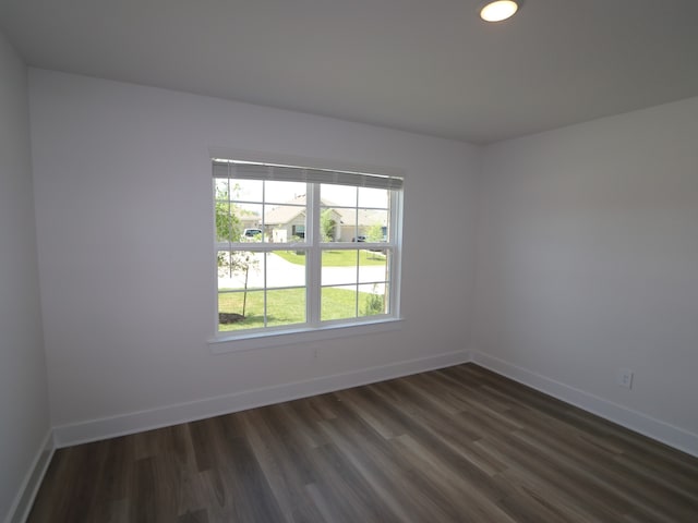 spare room with baseboards and dark wood finished floors