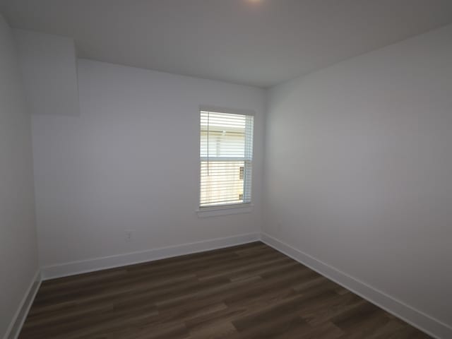 spare room featuring baseboards and dark wood finished floors
