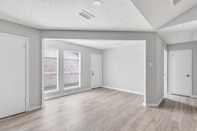 interior space featuring vaulted ceiling, a textured ceiling, and light hardwood / wood-style floors