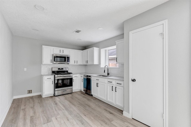 kitchen with tasteful backsplash, sink, stainless steel appliances, and white cabinetry