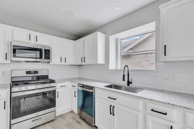 kitchen featuring appliances with stainless steel finishes, light hardwood / wood-style flooring, white cabinetry, and sink