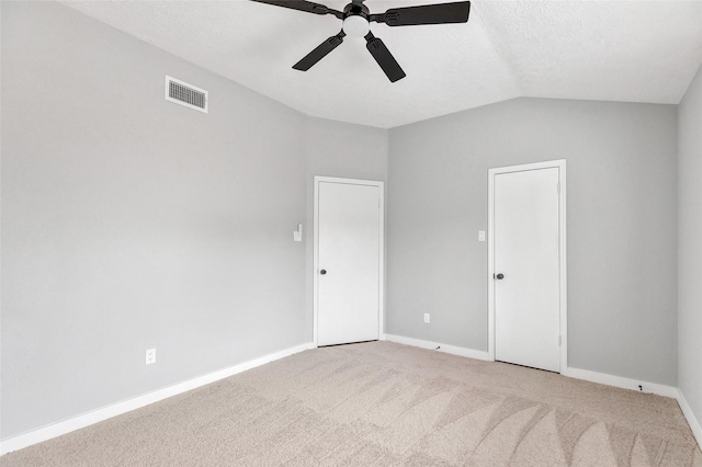 unfurnished room featuring ceiling fan, light colored carpet, vaulted ceiling, and a textured ceiling