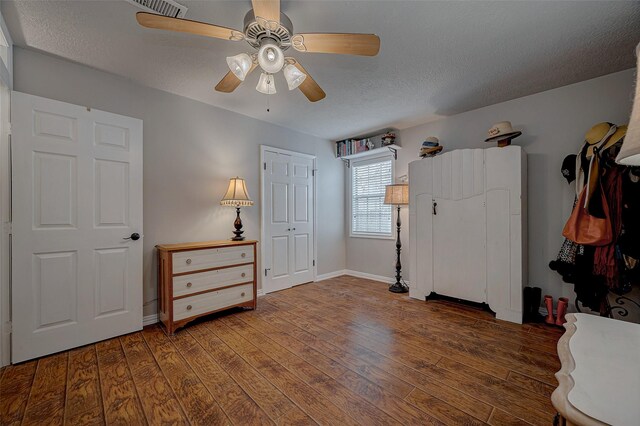 bedroom with a textured ceiling, dark wood-type flooring, a closet, and ceiling fan