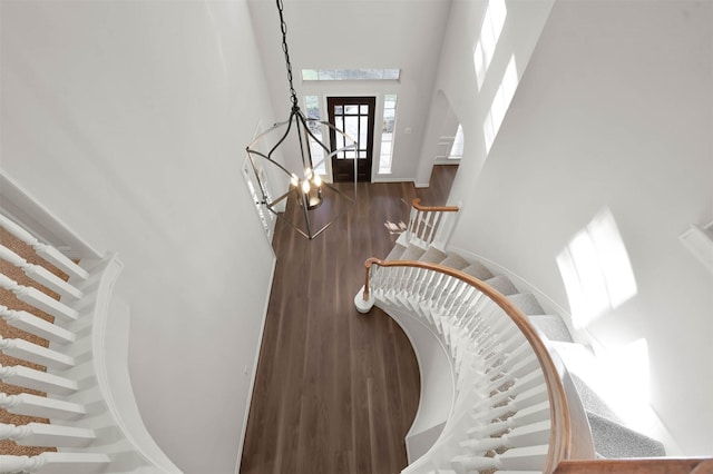 staircase with a chandelier and hardwood / wood-style floors